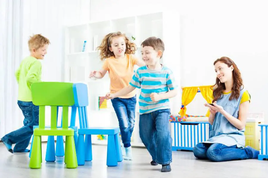 Crianças correndo ao redor das cadeiras brincando de dança das cadeiras