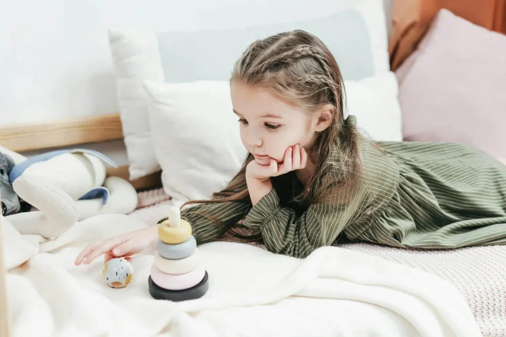 Criança em cima da cama brincando com brinquedo de madeira