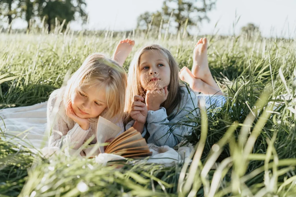 Duas meninas deitadas em um lençol no meio de uma grama alta