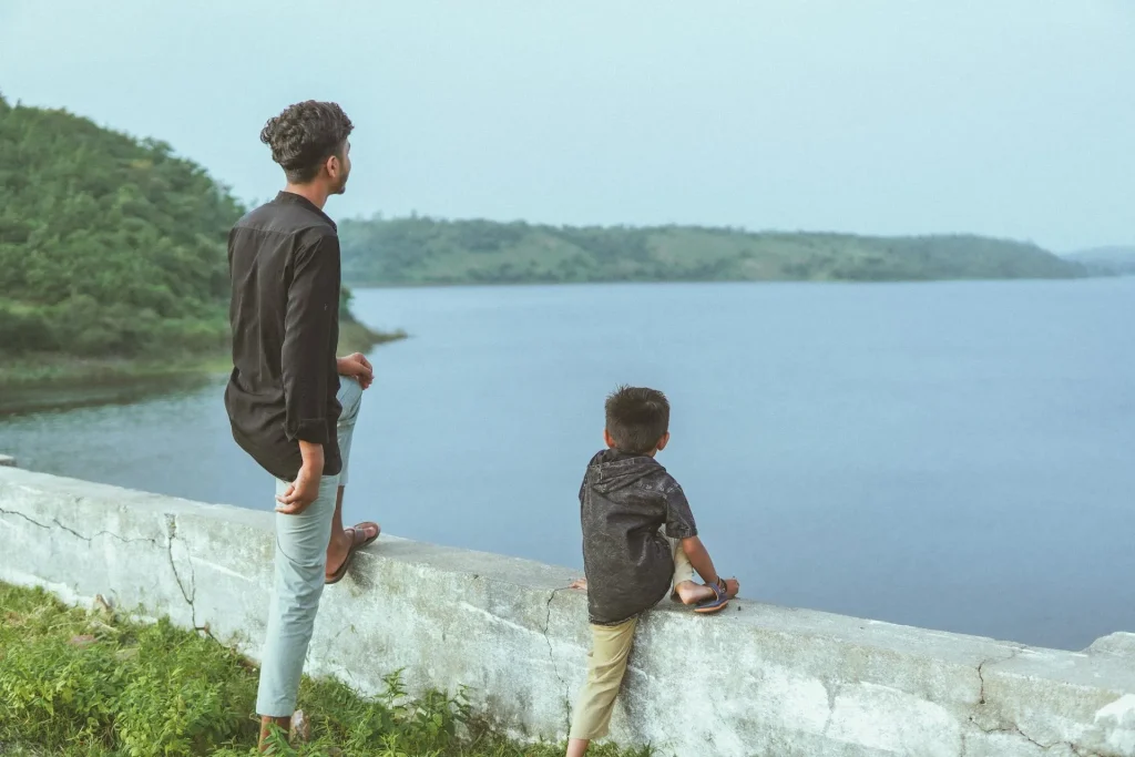 Pai e filho explorando o algo de uma barragem contemplando a natureza