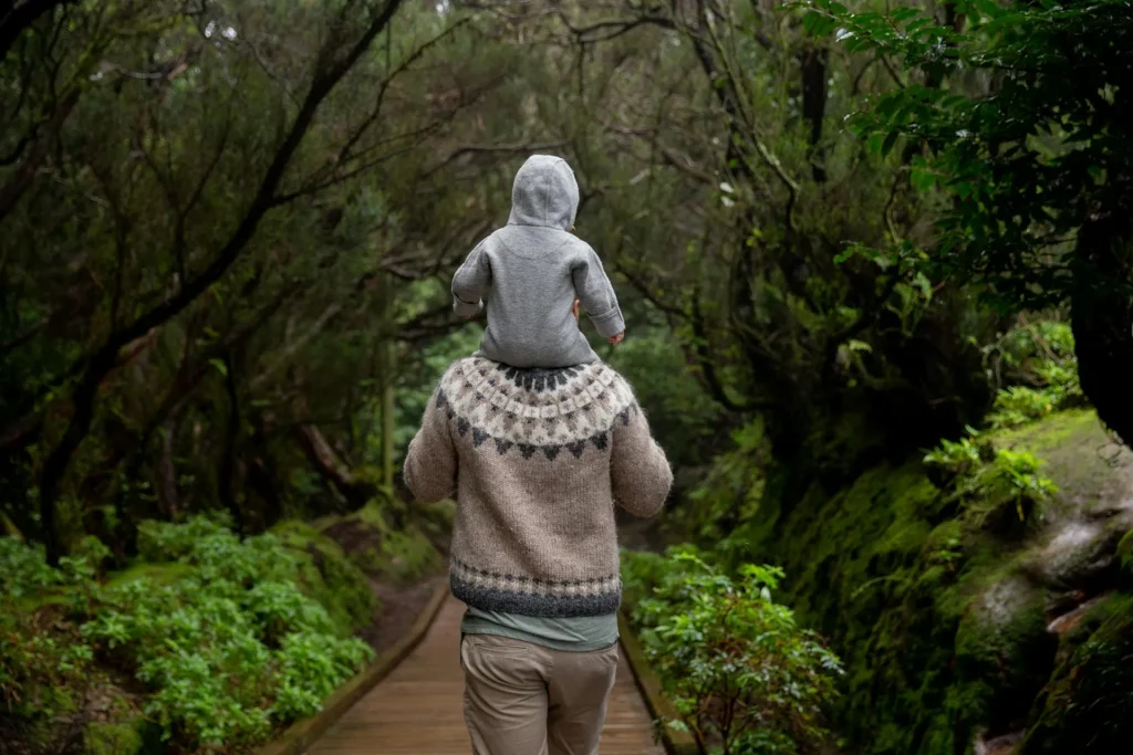 Pai levando criança para um passeio em meio a floresta